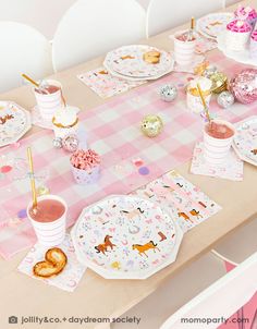 the table is set with pink and white plates, napkins, cups, and other decorations