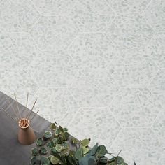 a vase sitting on top of a wooden table next to a plant and wallpaper