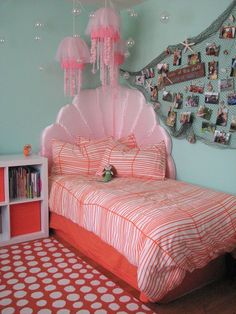 a bedroom decorated in pink and orange with pictures on the wall above the bed, along with bookshelves