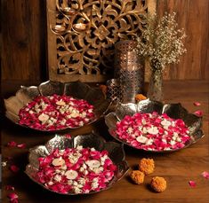 three metal bowls filled with flowers on top of a wooden table