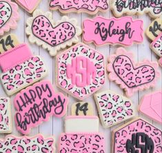 decorated cookies with pink and black frosting are arranged on a white surface, including the words happy birthday