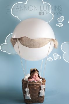 a baby in a basket with a balloon floating above it and thought bubbles coming out of the clouds