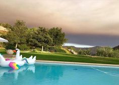 an inflatable swan float sitting on the edge of a swimming pool under a cloudy sky