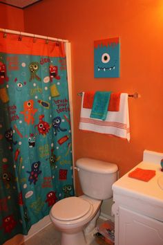 a bathroom with an orange wall and blue shower curtain, toilet and sink in it