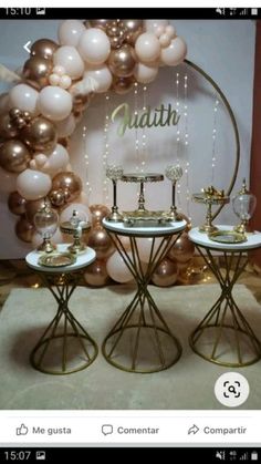 two tables with gold and white plates on them in front of a large balloon arch