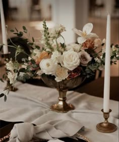 a centerpiece with flowers and candles on a table