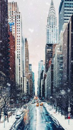 the city street is covered in snow as cars drive down it