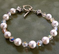 Real freshwater pearls and bright clear Swarovski crystals make for a lovely summer bracelet. Great with sundresses and wedding gowns. Wear this to dress up a casual t-shirt and jean shorts ensemble.Accented with Bali sterling silver and a heart toggle clasp. Handmade in Virginia. Give a gift that lasts a lifetime. Pearl is the birthstone for a woman born in June.Bracelet Details:- Freshwater pearls are 7 mm in diameter- Bracelet is 7.5 inches long (19.05 cm).- Sterling silver clasp- Pearl brace Elegant White Bracelet For Birthday, Pearl Bracelet With 8mm Round Beads For Wedding, 8mm Pearl Bead Bracelets For Weddings, Wedding Pearl Bracelet With 8mm Beads, Elegant Beaded Crystal Bracelet For Birthday, Elegant Handmade Crystal Bracelet For Birthday, Beaded Pearl Bracelet For Birthday, White Beaded Bracelet For Anniversary, White Crystal Pearl Bracelet Gift