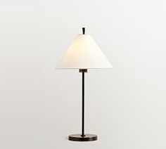 a lamp that is sitting on top of a wooden table next to a white wall