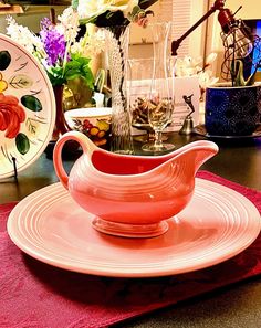 a pink saucer sitting on top of a plate next to a vase filled with flowers