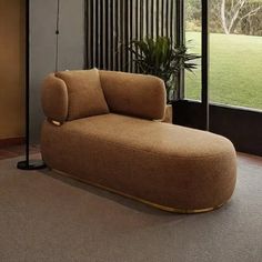 a living room with a large window and a couch in the corner next to a potted plant