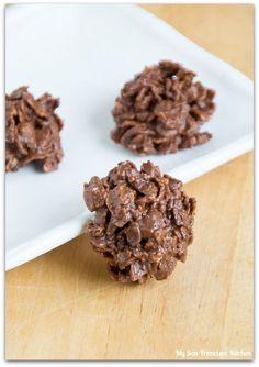 three chocolate cookies are on a white plate