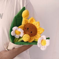 a person holding a stuffed animal with flowers in their hands and wearing a white t - shirt