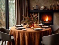 a dining room table set with plates and place settings in front of an open fireplace