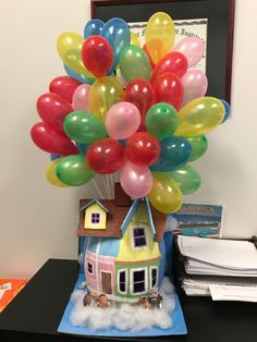 a house with balloons in the shape of a tree on top of it, next to a pile of books