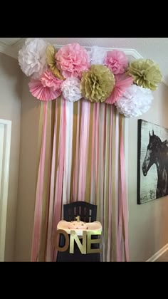 a chair sitting in front of a wall with flowers hanging from it's side