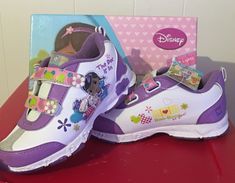 a pair of purple and white shoes sitting on top of a red table next to a box