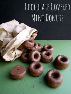 chocolate covered mini donuts sitting on top of a green table next to a bag