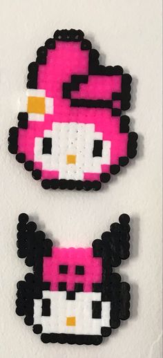 two pink and black hello kitty brooches on a white surface, one is made out of lego blocks