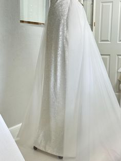 a white wedding dress on display in front of a mirror