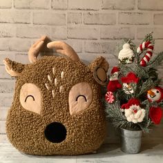 a stuffed animal purse sitting next to a potted plant with red flowers in it