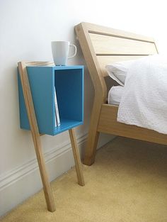 a blue shelf next to a bed with a white blanket on it and a cup in the corner