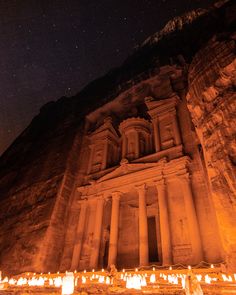 lit candles are placed in front of an ancient building at night with the stars above