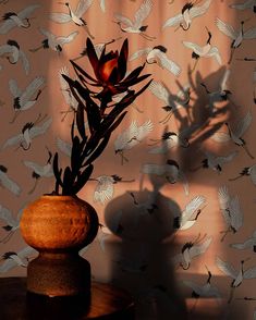 a vase filled with flowers sitting on top of a wooden table next to a wall