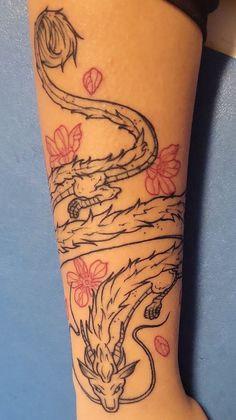 a tattoo on the leg of a woman with flowers and a dragon in her hair