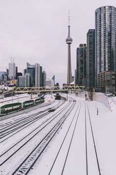 the train tracks are covered in snow near tall buildings