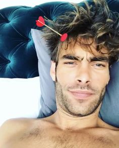 a shirtless man laying on top of a bed next to a blue headboard