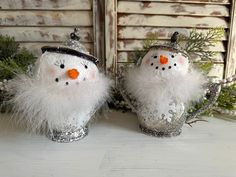 two snowmen with hats and feathers on their heads