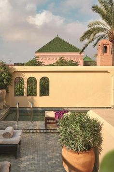 an outdoor patio with seating and potted plants on the side of the pool area