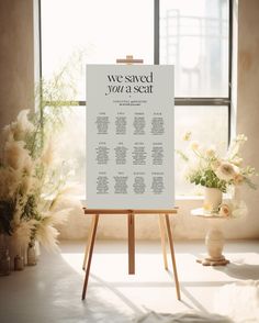 an easel with a wedding seating chart on it in front of a large window