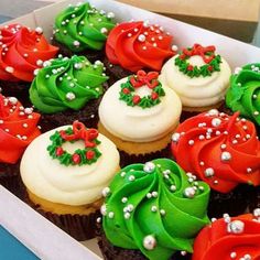 cupcakes decorated with green, red and white frosting are in a box