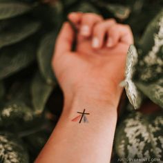 a person's arm with a small cross tattoo on it