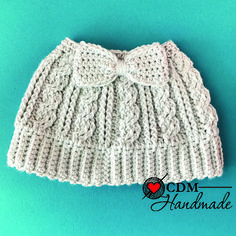 a white knitted hat with a bow on the front and side, against a blue background