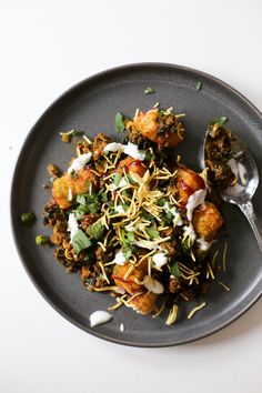 a black plate topped with meat and veggies on top of a white table