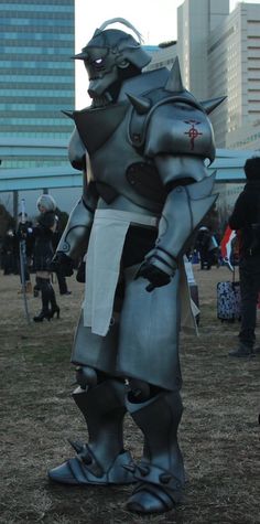 an inflatable robot standing on top of a field next to tall buildings and people