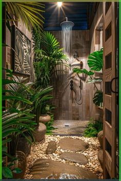 an outdoor shower surrounded by plants and rocks in a tropical style bathroom with green accents