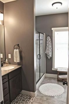 a bathroom with gray walls and white rugs on the floor, along with a walk in shower