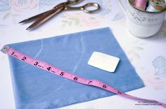 a measuring tape and scissors are sitting on a blue piece of cloth next to some crafting supplies