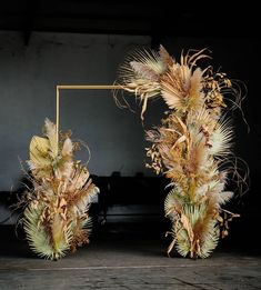 two vases with dried flowers in front of a black background and a gold frame