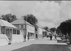 an old black and white photo of people walking down the street in front of houses