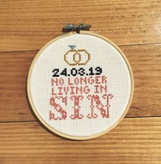 a cross - stitch hoop hanging on a wooden floor with the words, 2013 and two wedding rings