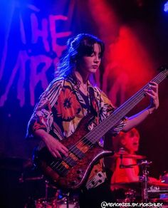 a man with long hair playing a guitar on stage