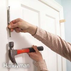 a person holding a hammer near a door with pins and nails attached to the handle