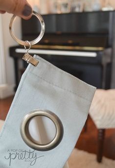 a person holding a keychain with a ring on it in front of a piano