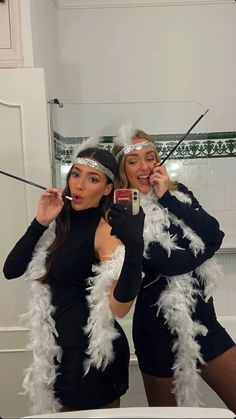 two women dressed in costumes taking a selfie with their cell phones while standing next to each other