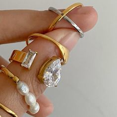 a woman's hand holding three rings with pearls and diamonds on each one ring